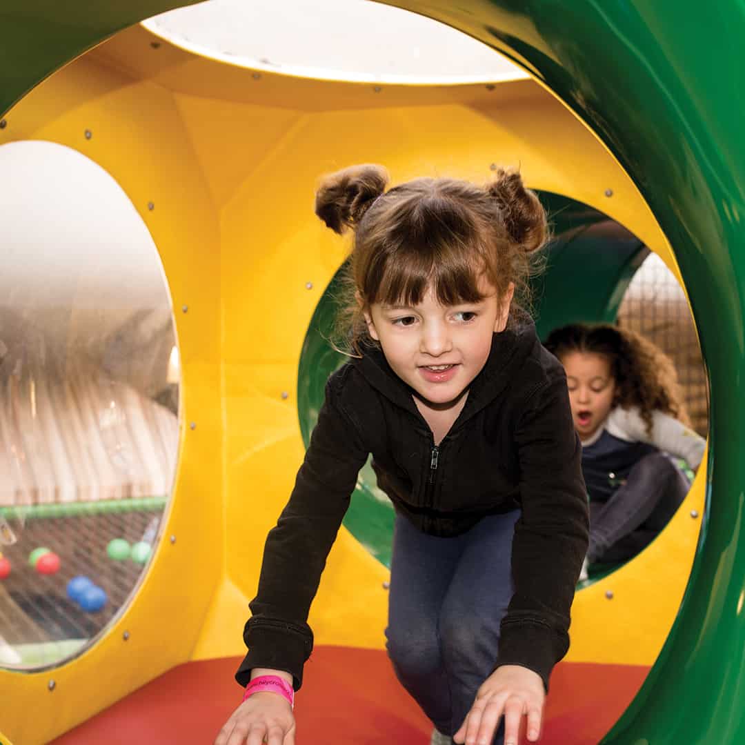 Girls climbing through tunnel on Soft Play